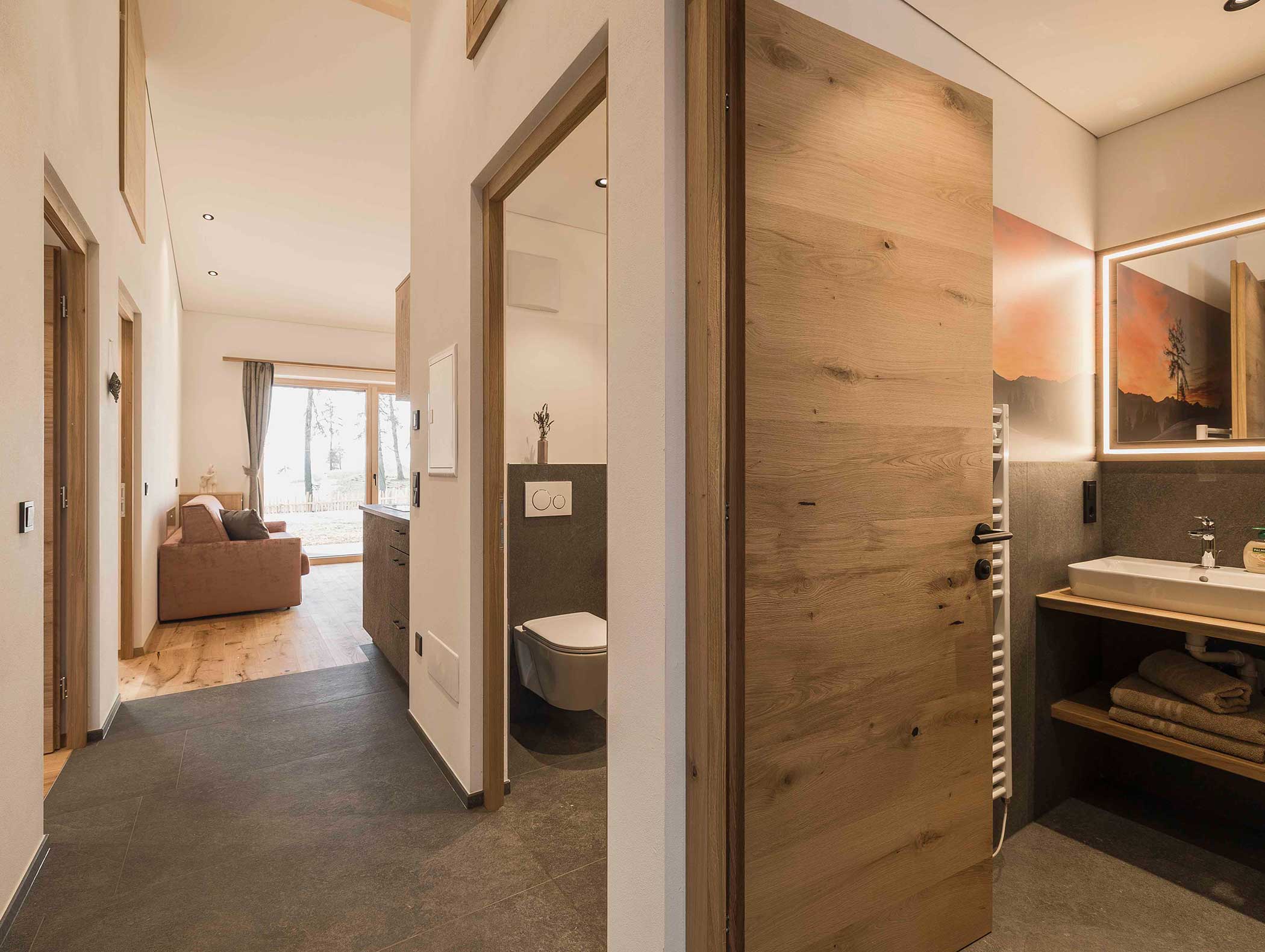 Modernes Apartment mit offenem Wohnbereich, Bad und Holzakzenten, sanft beleuchtet mit natürlichem Licht. - Langfennhof