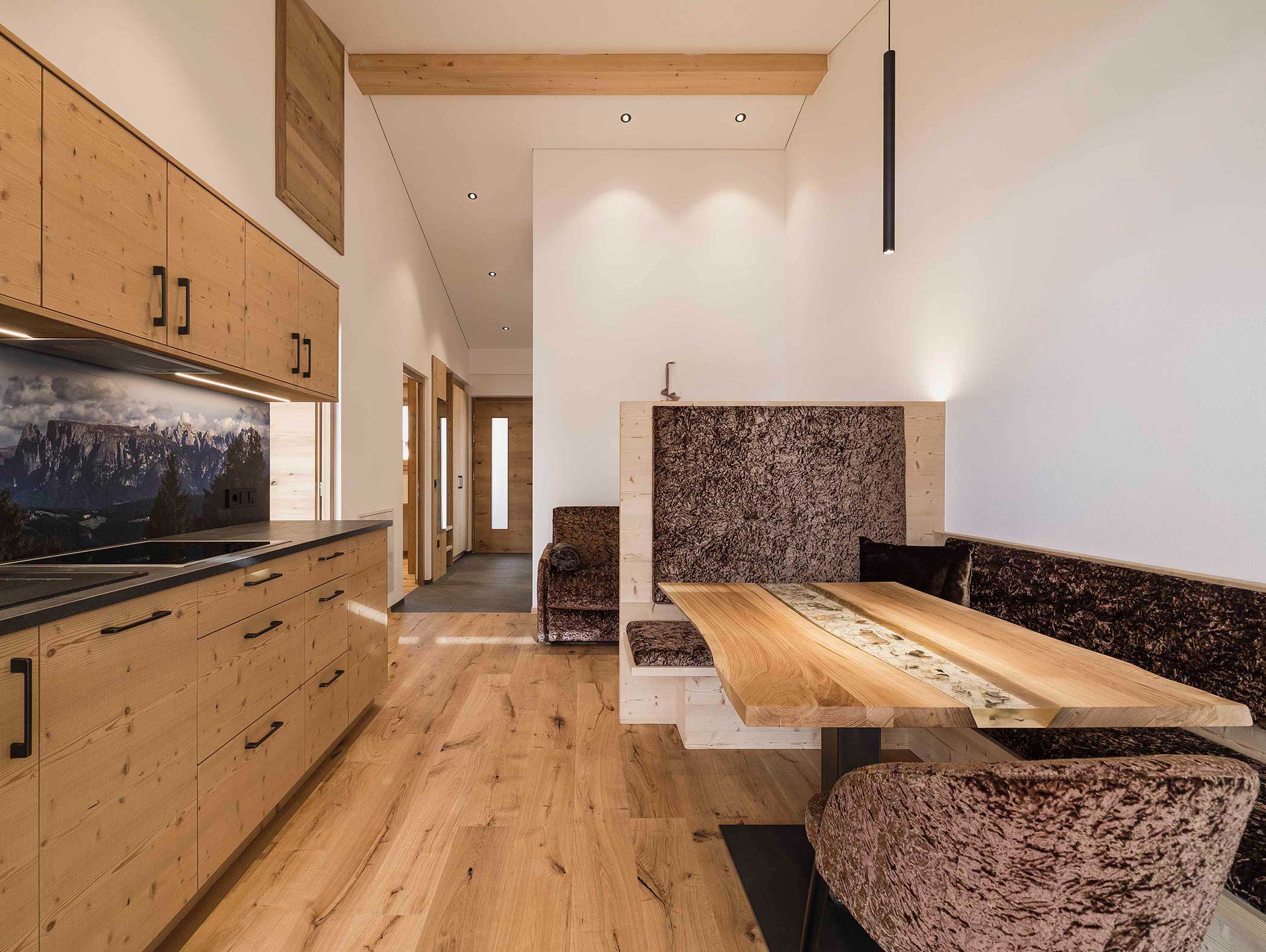 Moderne Küche mit Holzschränken, einem Esstisch und einer gemütlichen eingebauten Samtbank bei gedämpftem Licht. - Langfennhof