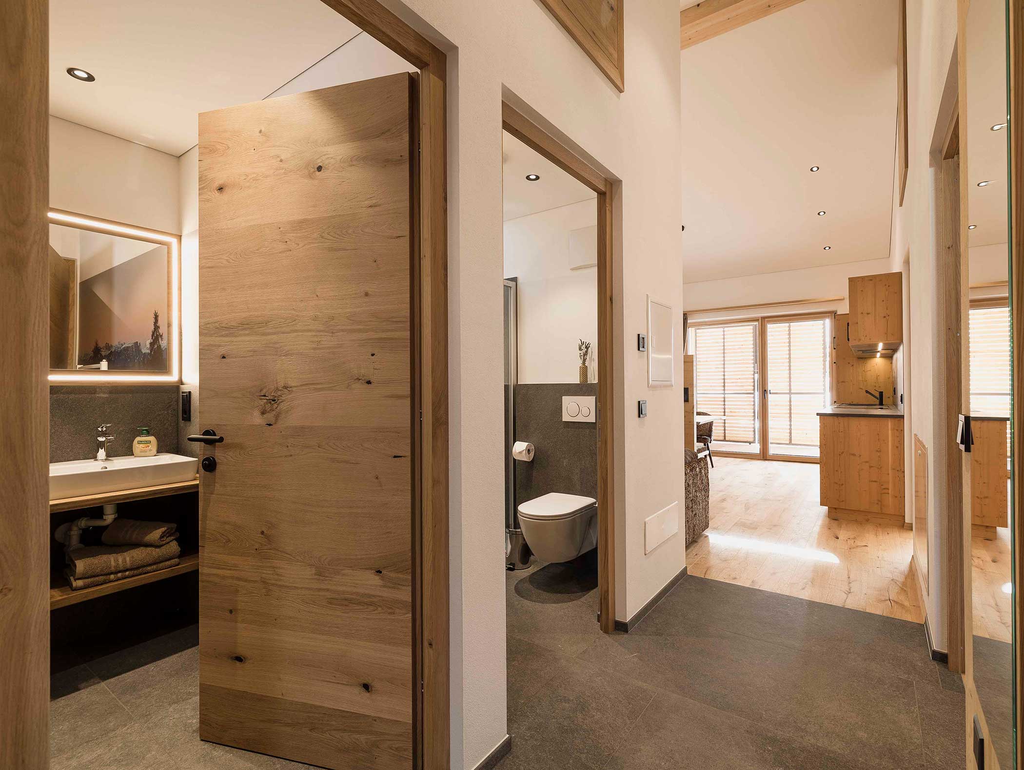 Modernes Apartment mit offenen Türen zu Bad, Schlafzimmer und Wohnbereich mit Holzakzenten. - Langfennhof