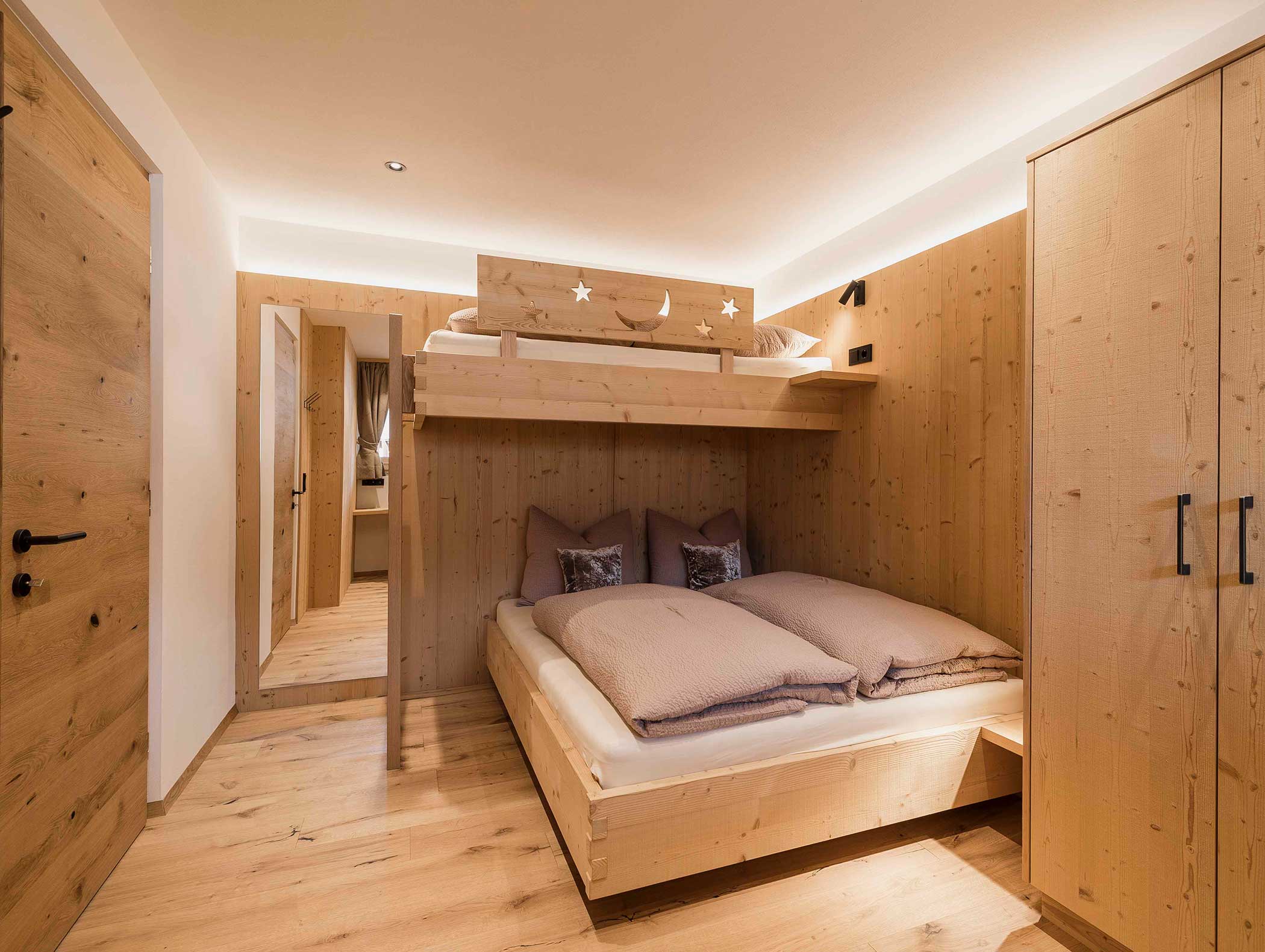 Modernes Holzschlafzimmer mit Doppelbett, hochgelegtem Einzelbett, Kleiderschrank und Wandspiegel. - Langfennhof